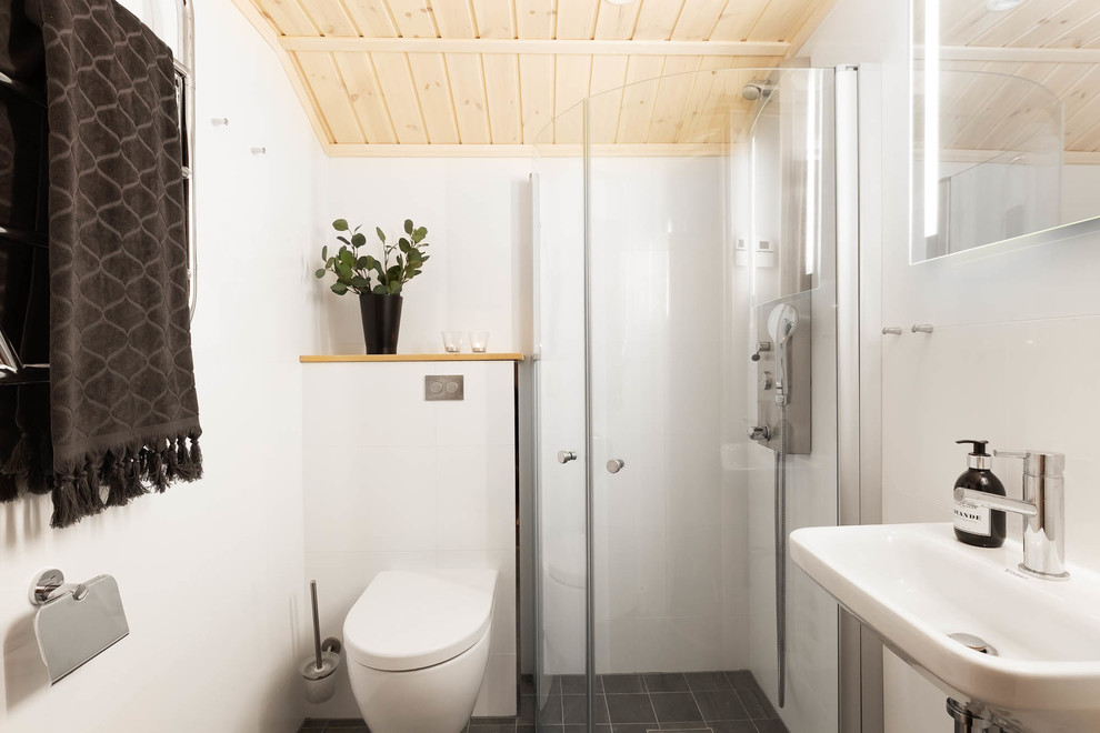 Idéer för ett minimalistiskt badrum, med en hörndusch, en vägghängd toalettstol, vit kakel, vita väggar, ett väggmonterat handfat, grått golv och dusch med skjutdörr