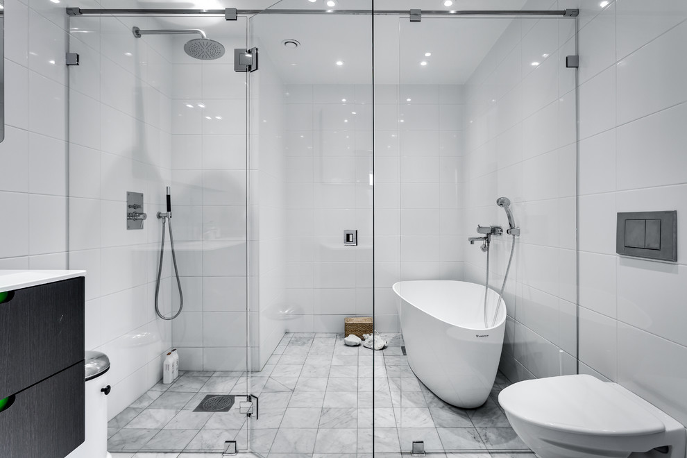 На фото: большая главная ванная комната в современном стиле с отдельно стоящей ванной, керамогранитной плиткой, мраморным полом, плоскими фасадами, темными деревянными фасадами, душем без бортиков, инсталляцией, белыми стенами и душем с распашными дверями с