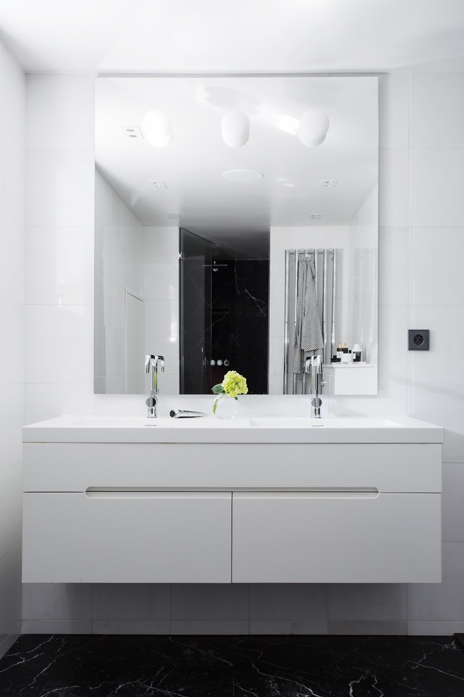 ストックホルムにあるお手頃価格のモダンスタイルのおしゃれな浴室 (フラットパネル扉のキャビネット、白いキャビネット、白い壁、磁器タイル、一体型シンク) の写真