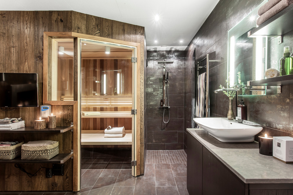 This is an example of an expansive contemporary ensuite bathroom in Gothenburg with open cabinets, concrete worktops, grey tiles, a walk-in shower, grey walls, a vessel sink, brown floors and an open shower.