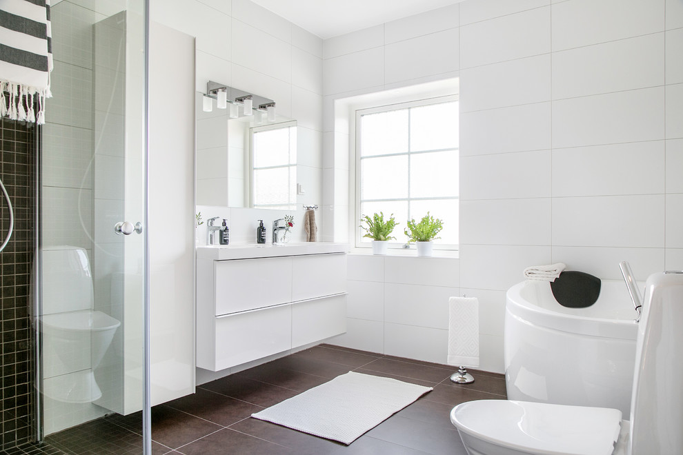 Cette photo montre une salle de bain principale tendance de taille moyenne avec un placard à porte plane, des portes de placard blanches, une baignoire indépendante, un carrelage noir et blanc, un mur blanc et un plan vasque.
