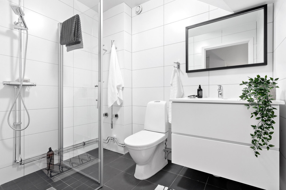Idéer för att renovera ett litet skandinaviskt vit vitt badrum med dusch, med släta luckor, vita skåp, vit kakel, vita väggar, grått golv, en hörndusch, en toalettstol med hel cisternkåpa, porslinskakel och klinkergolv i porslin
