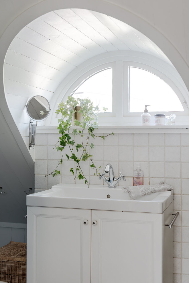 Idéer för lantliga badrum, med luckor med infälld panel, vita skåp, vit kakel, porslinskakel, vita väggar och ett integrerad handfat
