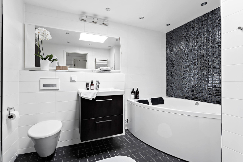 Foto di una stanza da bagno moderna di medie dimensioni con ante nere, WC sospeso, pavimento nero, consolle stile comò, piastrelle multicolore, pareti multicolore, pavimento con piastrelle in ceramica e lavabo sospeso