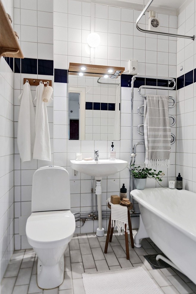 Imagen de cuarto de baño escandinavo pequeño con bañera con patas, sanitario de una pieza, baldosas y/o azulejos blancos, paredes blancas, aseo y ducha, lavabo suspendido y suelo blanco