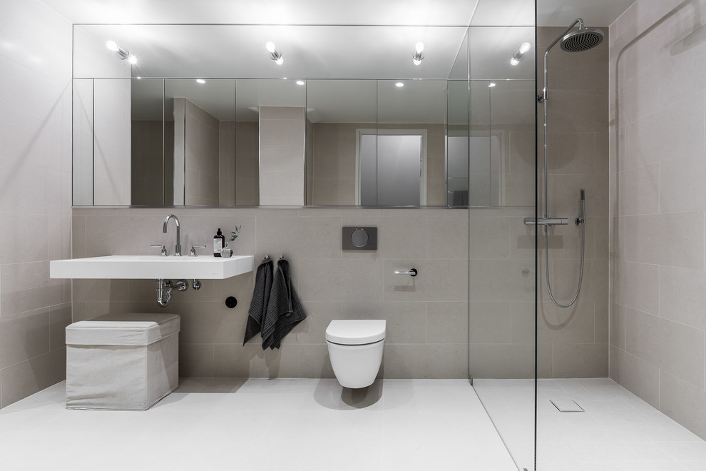 Modelo de cuarto de baño contemporáneo grande con sanitario de pared, baldosas y/o azulejos beige, paredes beige, lavabo de seno grande y suelo blanco