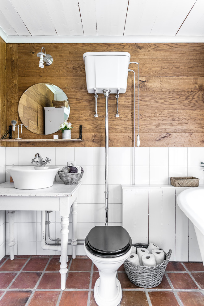 Foto på ett mellanstort lantligt badrum, med vita skåp, en toalettstol med separat cisternkåpa, vit kakel, flerfärgade väggar och ett fristående handfat