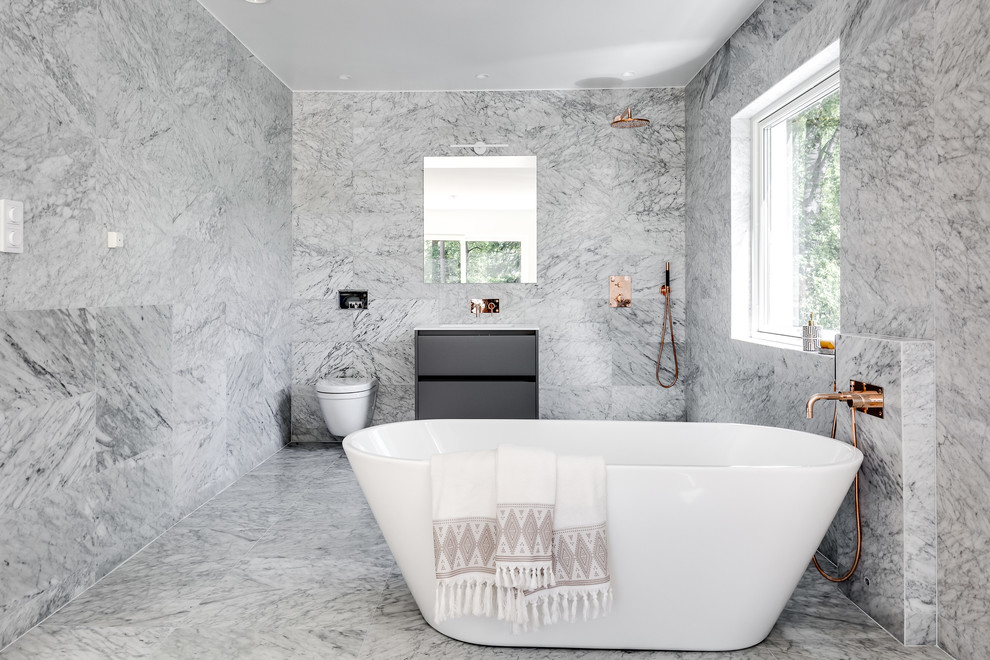 Modern inredning av ett stort badrum, med släta luckor, ett fristående badkar, en dusch/badkar-kombination, marmorkakel och marmorgolv