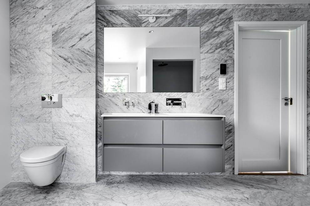 Ispirazione per una grande stanza da bagno minimal con ante lisce, ante grigie, WC sospeso e pavimento in marmo