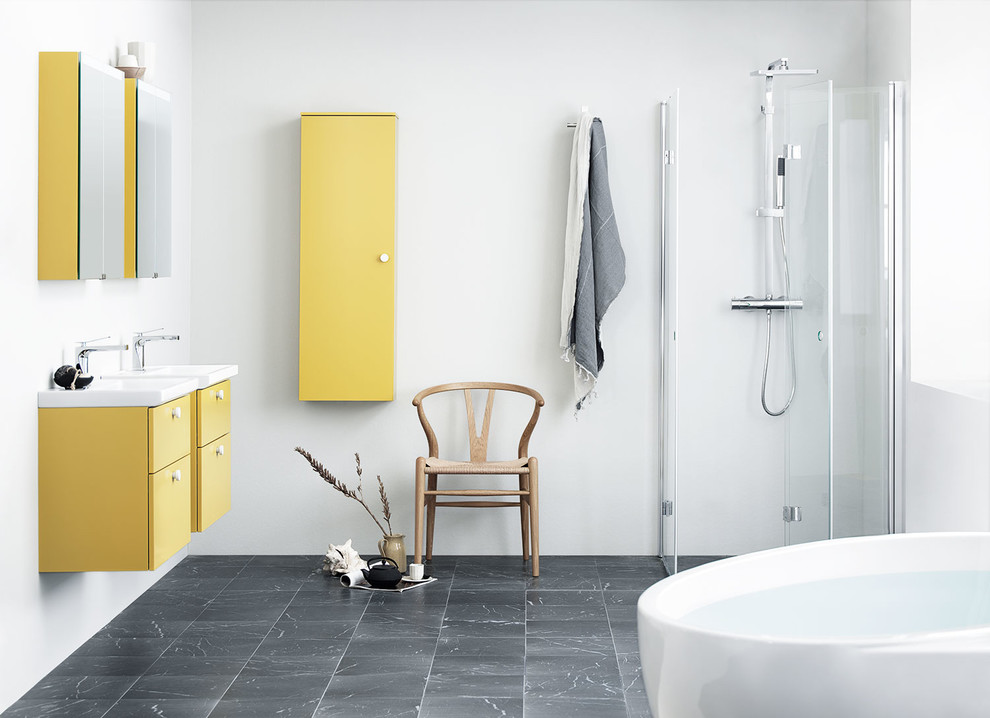 Стильный дизайн: ванная комната среднего размера в скандинавском стиле с плоскими фасадами, желтыми фасадами, отдельно стоящей ванной, белыми стенами, мраморным полом, душевой кабиной, подвесной раковиной, черным полом и душем с распашными дверями - последний тренд