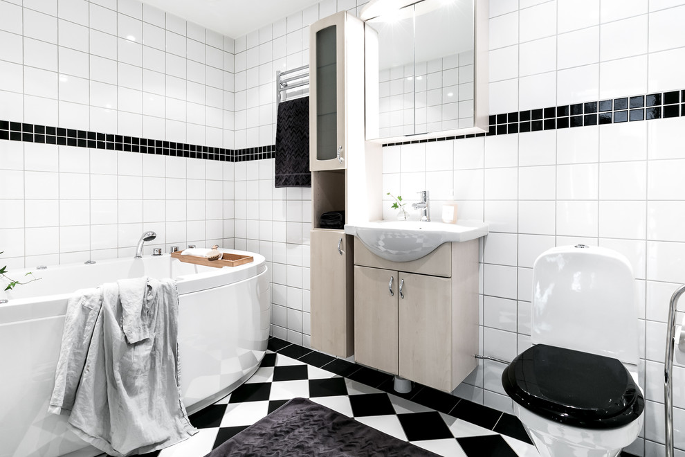 Exempel på ett mellanstort klassiskt en-suite badrum, med släta luckor, beige skåp, vita väggar, flerfärgat golv, ett fristående badkar, en toalettstol med hel cisternkåpa, svart och vit kakel och ett konsol handfat