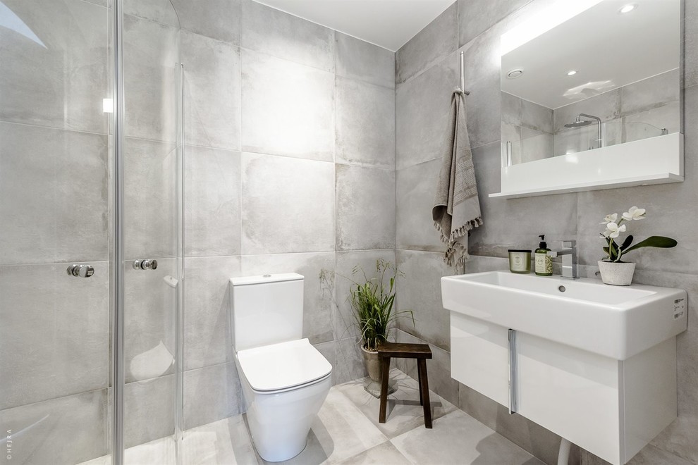 Photo of a contemporary shower room bathroom in Stockholm with flat-panel cabinets, white cabinets, a corner shower, a two-piece toilet, grey walls, an integrated sink, cement tiles, limestone flooring and concrete worktops.