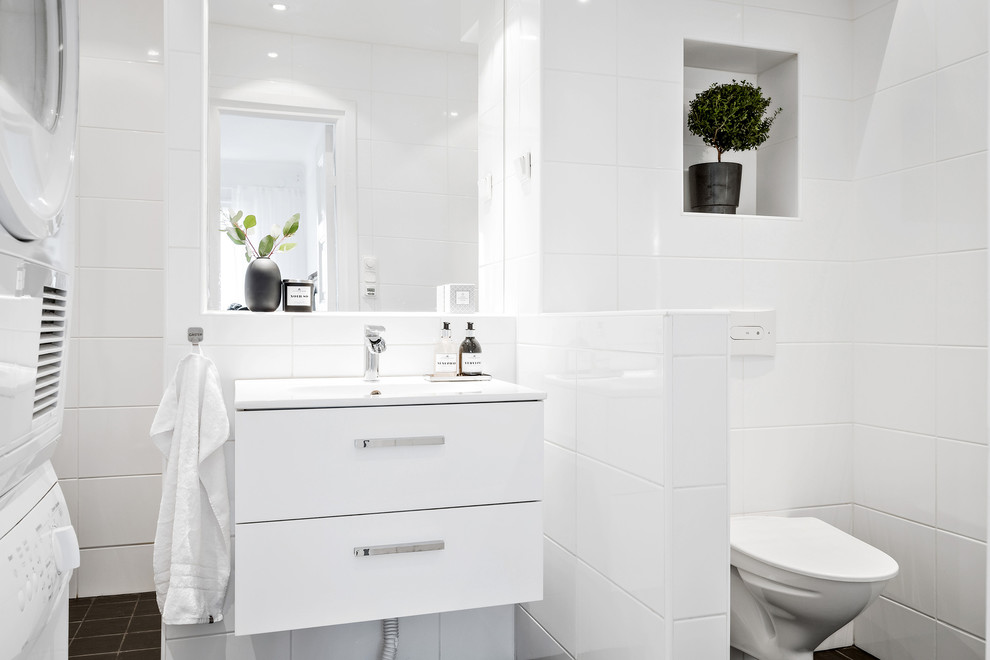 Inspiration för skandinaviska badrum med dusch, med släta luckor, vita skåp, en hörndusch, en vägghängd toalettstol, vit kakel, vita väggar, ett integrerad handfat, svart golv och med dusch som är öppen