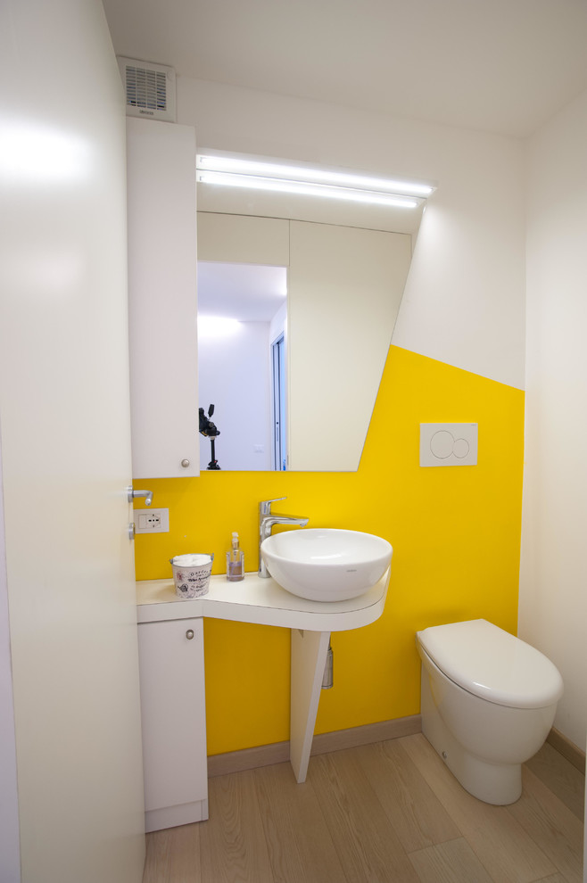 Immagine di un piccolo bagno di servizio contemporaneo con ante lisce, ante bianche, WC monopezzo, pareti grigie, lavabo a bacinella, top in laminato e pavimento marrone