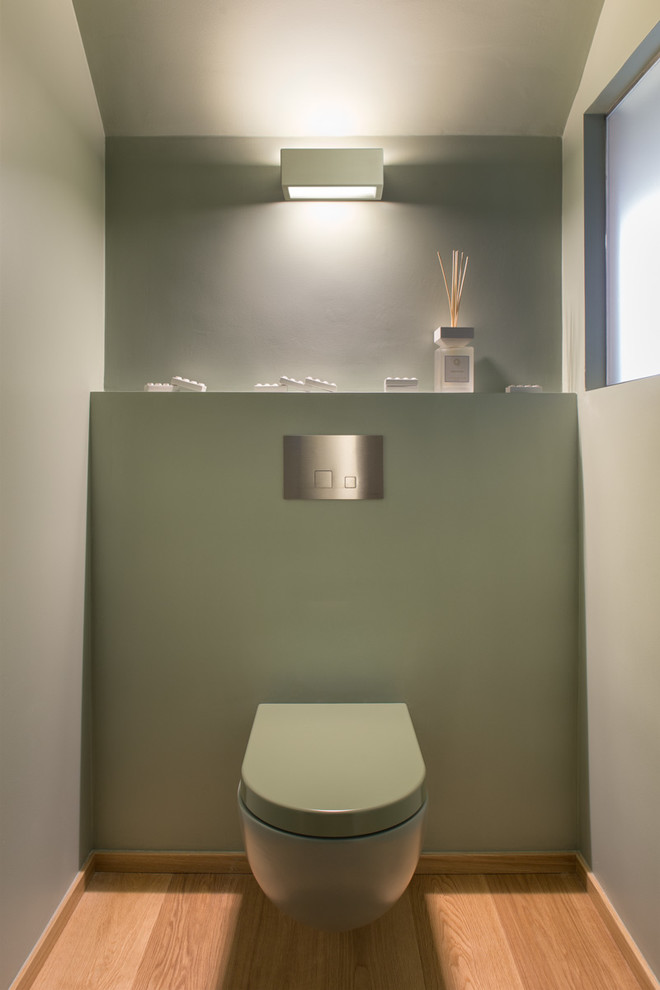 ミラノにある小さなコンテンポラリースタイルのおしゃれなトイレ・洗面所 (壁掛け式トイレ、緑の壁、淡色無垢フローリング) の写真