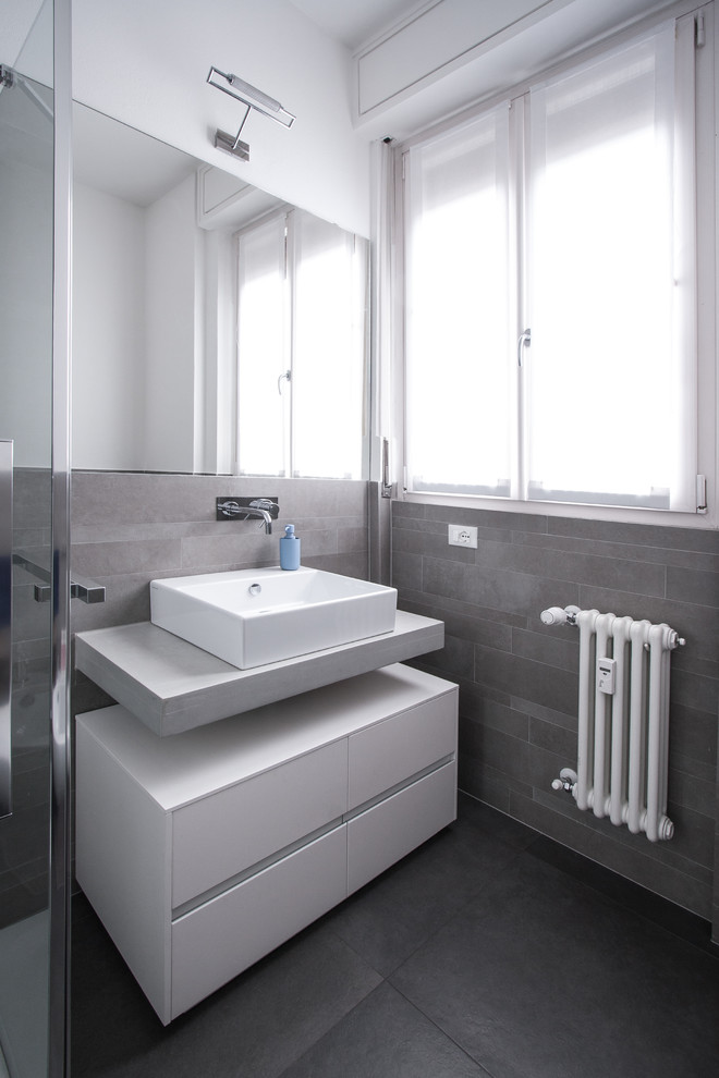 Modern inredning av ett litet toalett, med släta luckor, vita skåp, klinkergolv i porslin och grått golv