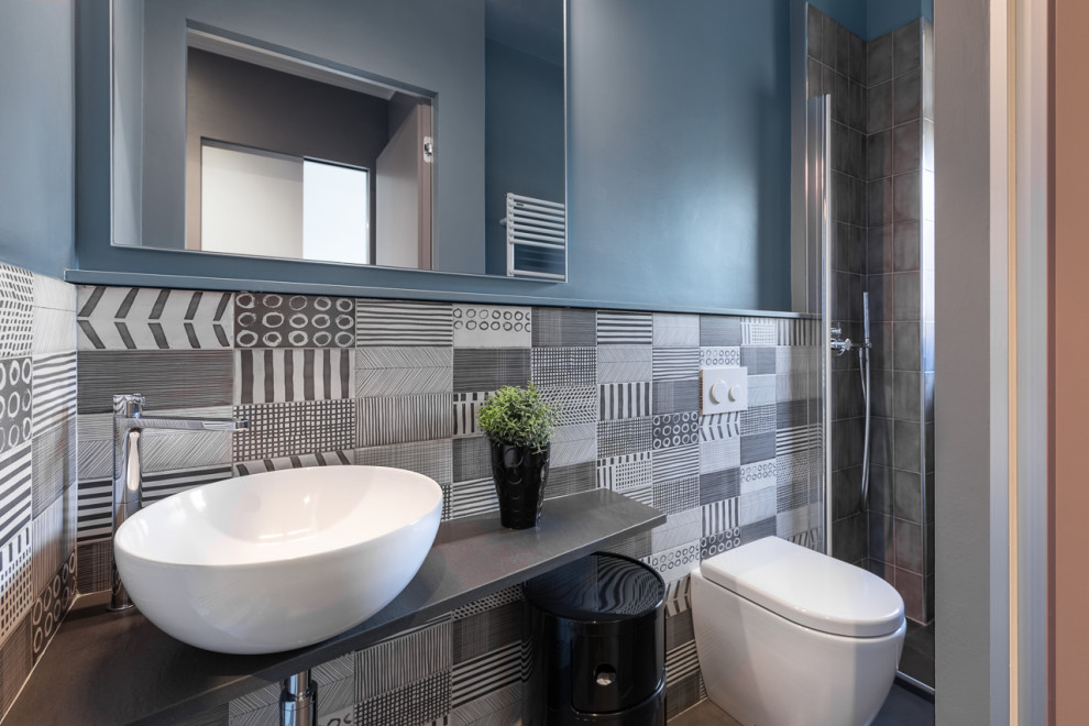 Пример оригинального дизайна: маленький туалет в современном стиле с черно-белой плиткой, керамической плиткой, синими стенами, полом из керамической плитки, настольной раковиной, серым полом и черной столешницей для на участке и в саду