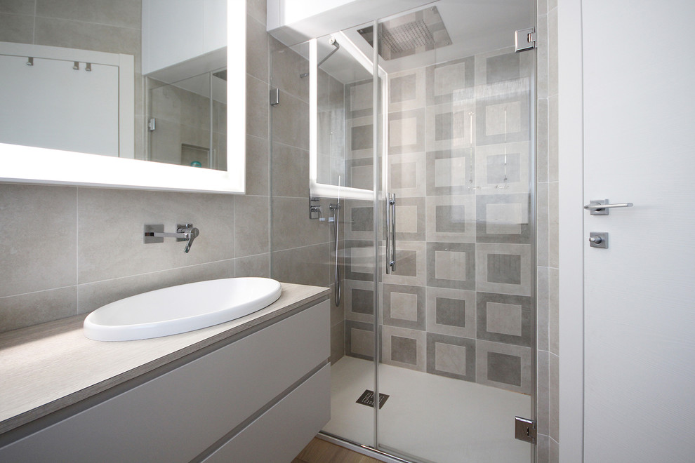 Photo of a medium sized modern cloakroom in Other with flat-panel cabinets, light hardwood flooring, beige cabinets, a one-piece toilet, ceramic tiles, beige walls, a built-in sink, brown floors, multi-coloured tiles, quartz worktops and beige worktops.