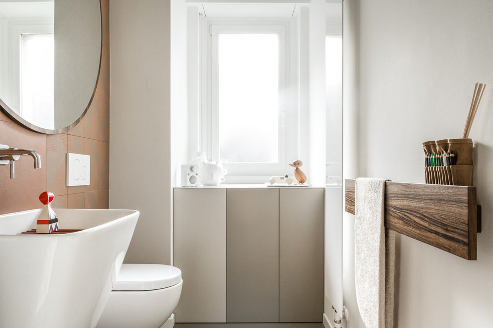 Cette image montre un petit WC suspendu design avec un placard à porte plane, des carreaux de porcelaine, un sol en carrelage de porcelaine et un sol beige.