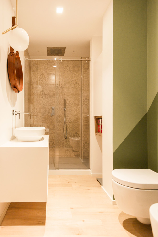 This is an example of a small scandinavian cloakroom in Milan with flat-panel cabinets, white cabinets, a two-piece toilet, multi-coloured tiles, ceramic tiles, multi-coloured walls, light hardwood flooring, a vessel sink, wooden worktops and white worktops.
