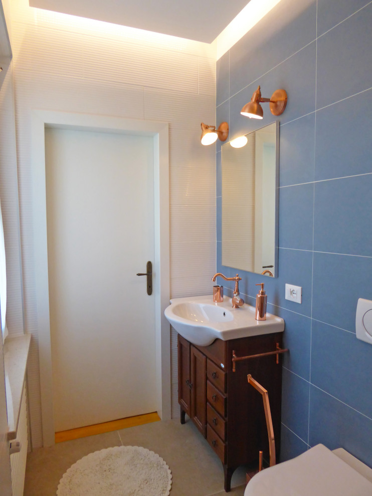 На фото: маленький туалет в стиле модернизм с фасадами островного типа, коричневыми фасадами, раздельным унитазом, оранжевой плиткой, керамогранитной плиткой, синими стенами, полом из керамогранита, монолитной раковиной, столешницей из плитки, бежевым полом, белой столешницей, напольной тумбой, многоуровневым потолком и панелями на части стены для на участке и в саду
