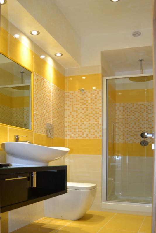 Cette photo montre un petit WC et toilettes moderne en bois foncé avec un placard sans porte, WC à poser, un carrelage jaune, mosaïque, un mur beige, un sol en carrelage de porcelaine, une vasque et un plan de toilette en bois.