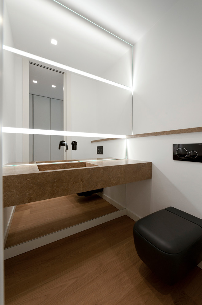Idee per un bagno di servizio minimalista con pareti bianche, pavimento in legno massello medio, lavabo integrato e top beige