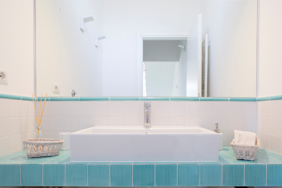 Bild på ett litet maritimt badrum, med öppna hyllor, en toalettstol med separat cisternkåpa, vit kakel, keramikplattor, vita väggar, klinkergolv i keramik, ett avlångt handfat, kaklad bänkskiva och grönt golv