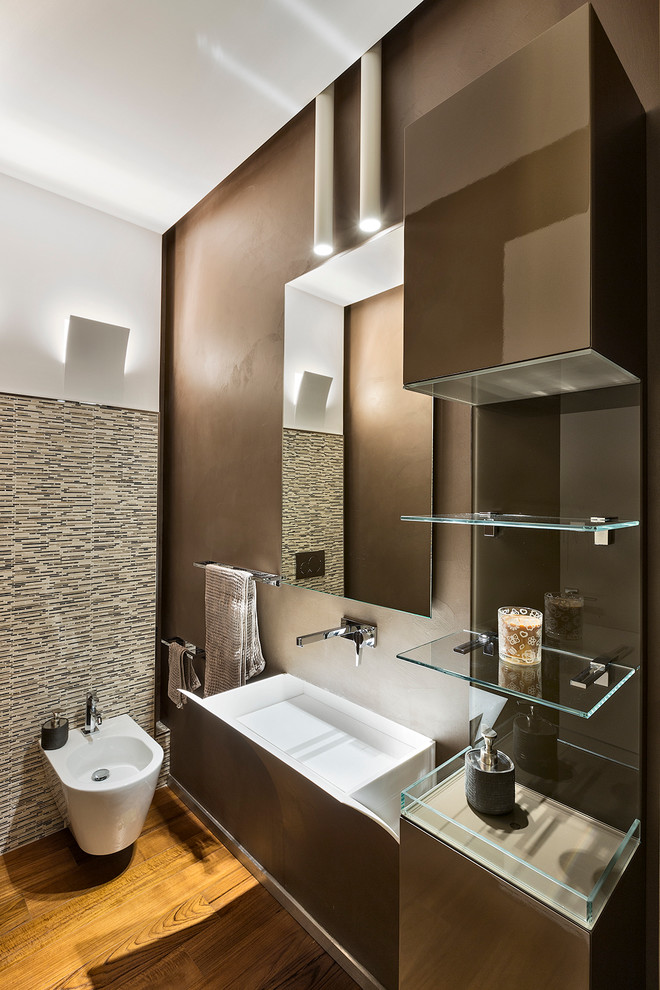 Idée de décoration pour un WC et toilettes design de taille moyenne avec un placard à porte plane, des portes de placard marrons, WC séparés, un mur marron, un sol en bois brun et un lavabo suspendu.