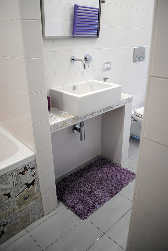 Inredning av ett modernt litet toalett, med en toalettstol med separat cisternkåpa, vit kakel, porslinskakel, vita väggar, klinkergolv i porslin, ett fristående handfat, kaklad bänkskiva och grått golv
