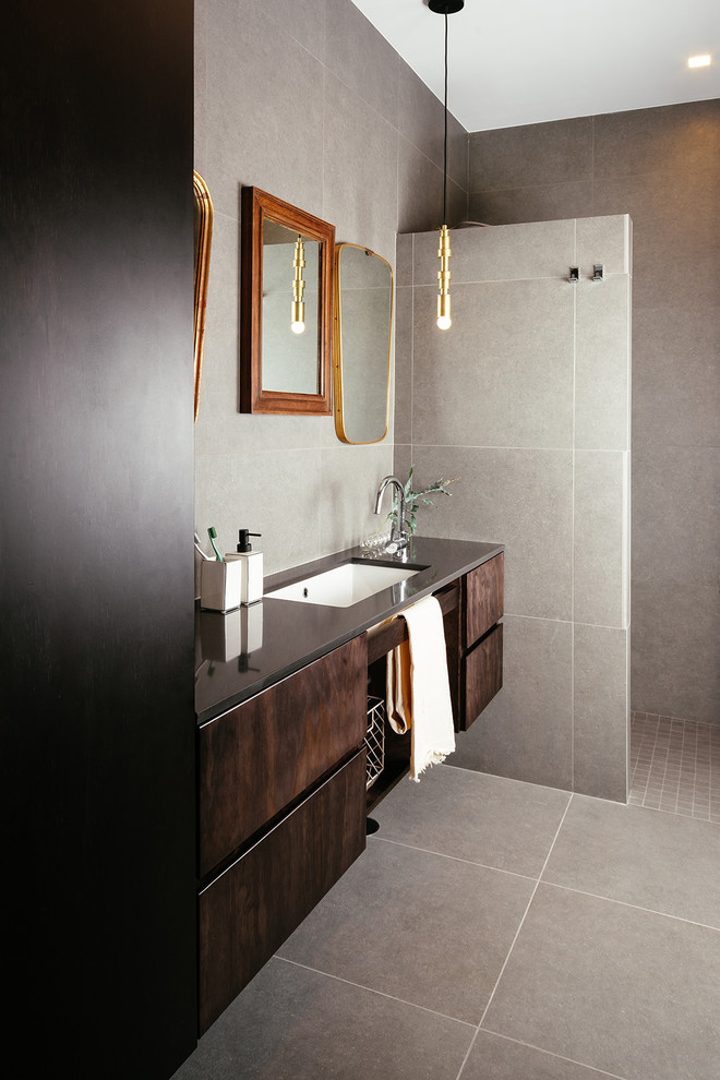 Cette image montre un WC suspendu design en bois foncé avec un placard à porte plane, un carrelage gris, des carreaux de porcelaine, un sol en carrelage de porcelaine, une vasque, un plan de toilette en bois, un sol gris et un plan de toilette marron.