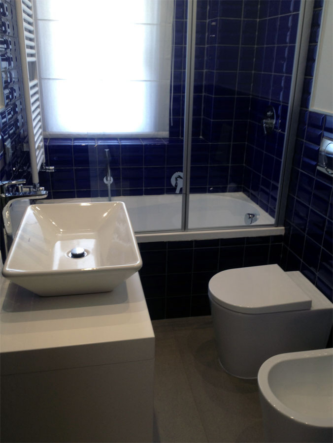 Inspiration för små moderna vitt toaletter, med öppna hyllor, vita skåp, en toalettstol med separat cisternkåpa, blå kakel, porslinskakel, vita väggar, klinkergolv i porslin, ett fristående handfat, träbänkskiva och grått golv