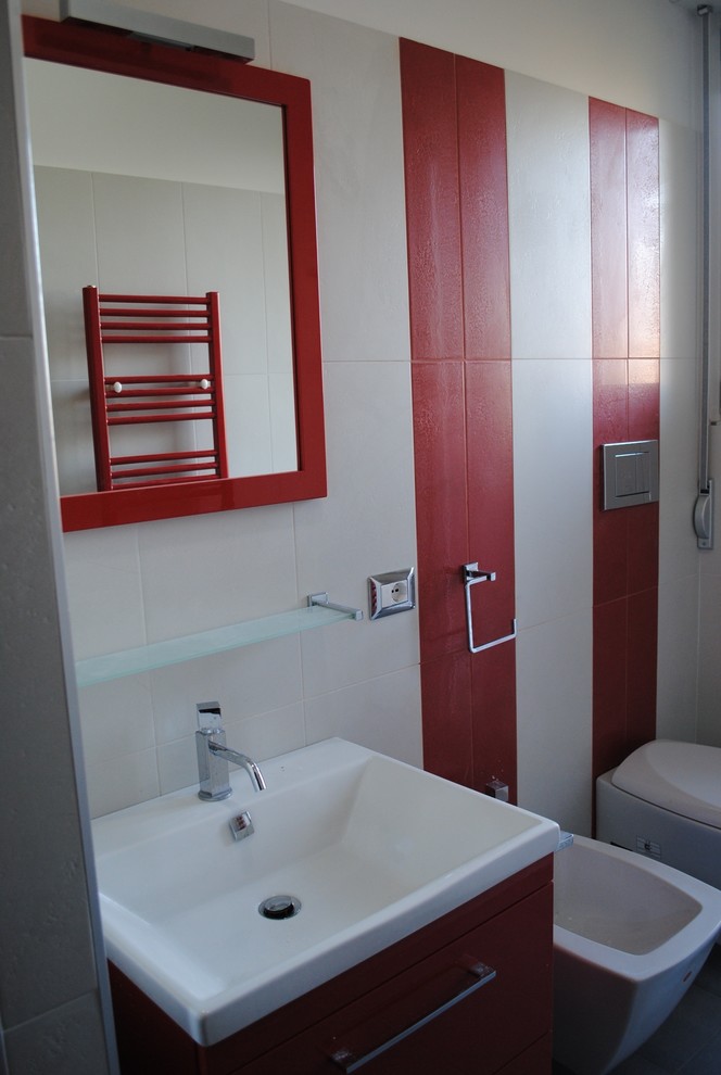 Cette photo montre un WC suspendu tendance de taille moyenne avec un placard à porte plane, des portes de placard rouges, un carrelage rouge, un carrelage blanc, des carreaux de porcelaine, un mur blanc, un sol en carrelage de porcelaine, un lavabo intégré et un sol gris.