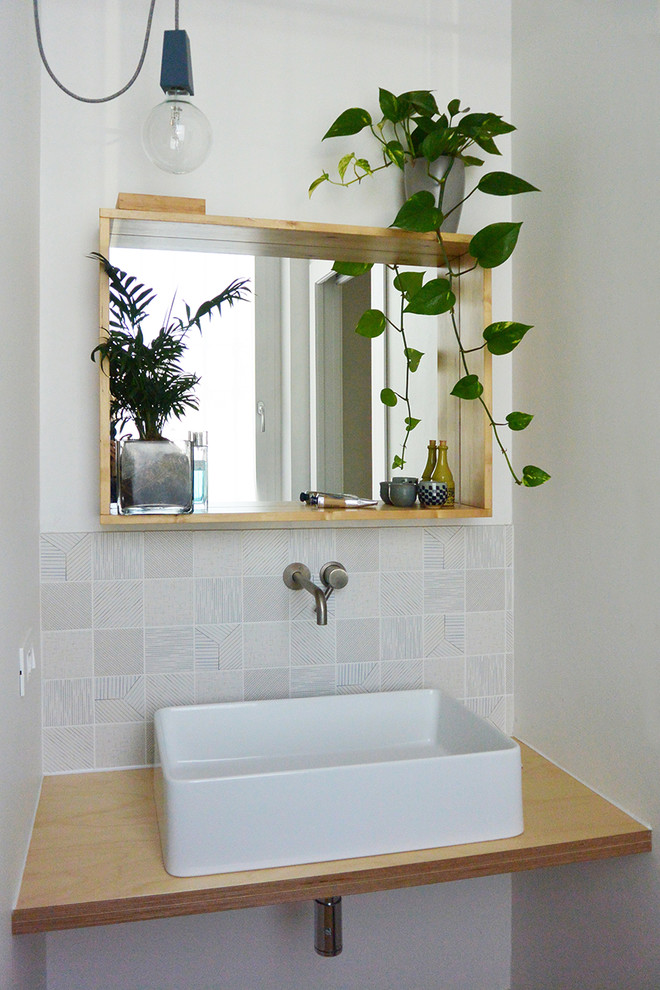 Стильный дизайн: маленький туалет в скандинавском стиле с раздельным унитазом, белой плиткой, керамической плиткой, белыми стенами, деревянным полом, настольной раковиной и столешницей из дерева для на участке и в саду - последний тренд