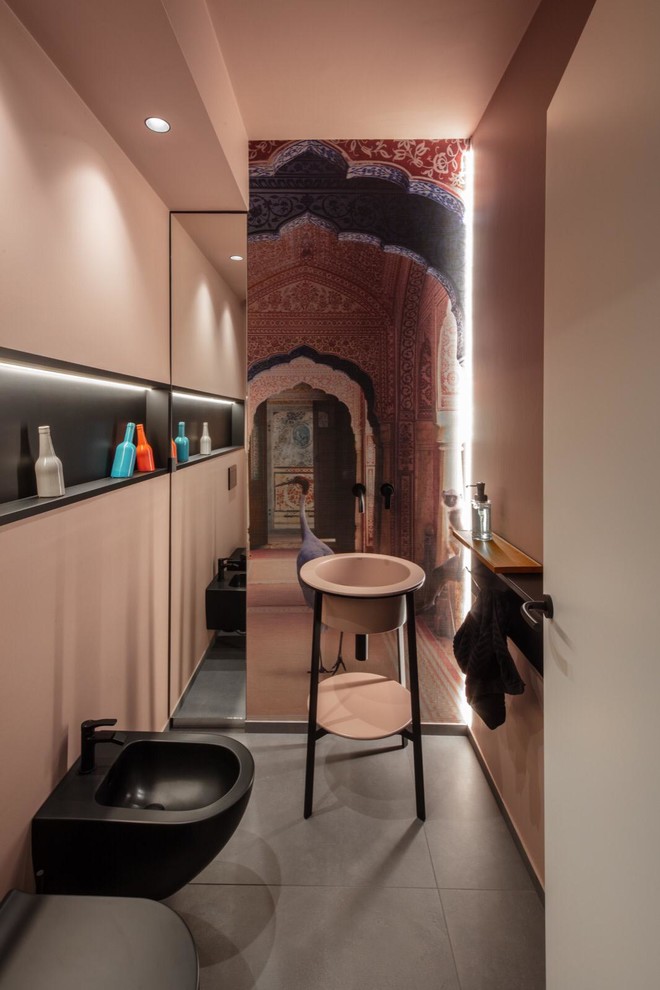 Foto på ett mellanstort funkis rosa toalett, med svarta skåp, en toalettstol med separat cisternkåpa, grå kakel, rosa väggar, klinkergolv i porslin, ett piedestal handfat, bänkskiva i akrylsten och grått golv