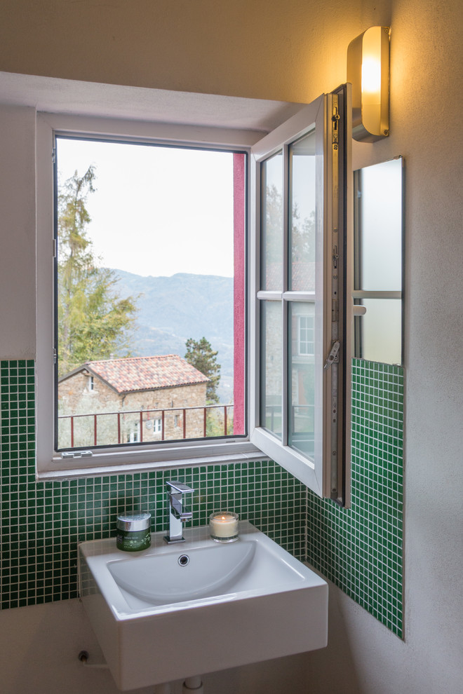 Bild på ett litet funkis toalett, med grön kakel, mosaik, vita väggar och ett avlångt handfat