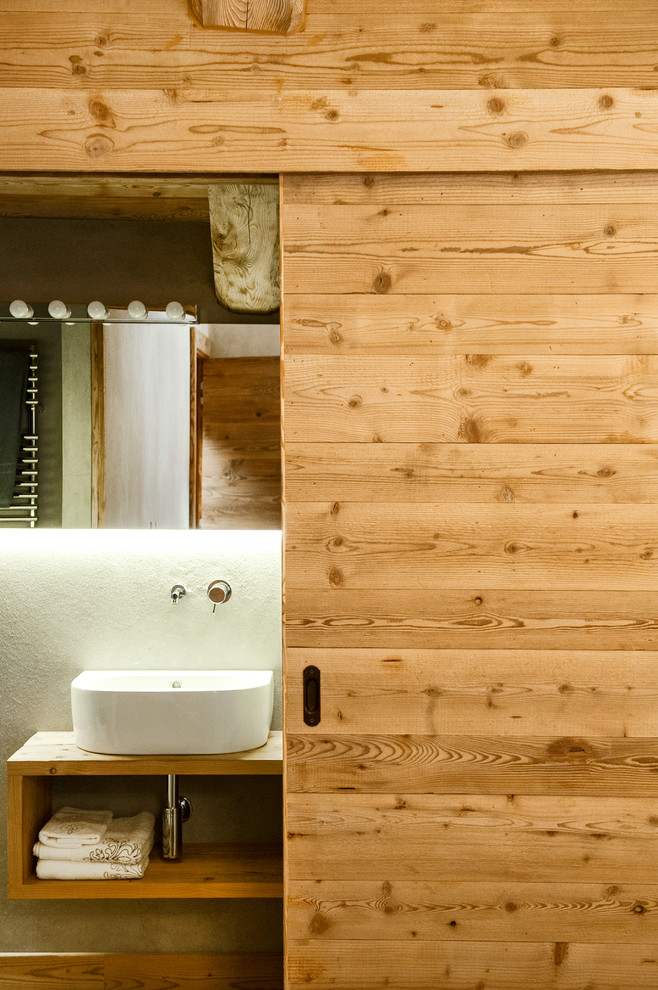 Foto di un piccolo bagno di servizio rustico con nessun'anta, ante in legno chiaro, WC sospeso, pavimento in legno massello medio, top in legno, pareti bianche e lavabo a bacinella