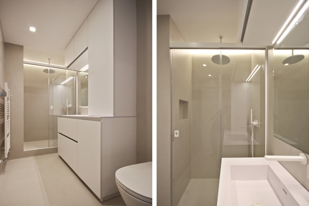 This is an example of a medium sized contemporary bathroom in Milan with flat-panel cabinets, beige cabinets, a one-piece toilet, beige tiles, beige walls, concrete flooring, an integrated sink, solid surface worktops, beige floors and beige worktops.