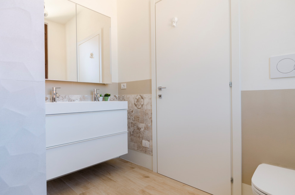 Design ideas for a small modern cloakroom in Milan with flat-panel cabinets, white cabinets, a two-piece toilet, multi-coloured tiles, porcelain tiles, beige walls, wood-effect flooring, an integrated sink, engineered stone worktops, beige floors, white worktops and a floating vanity unit.