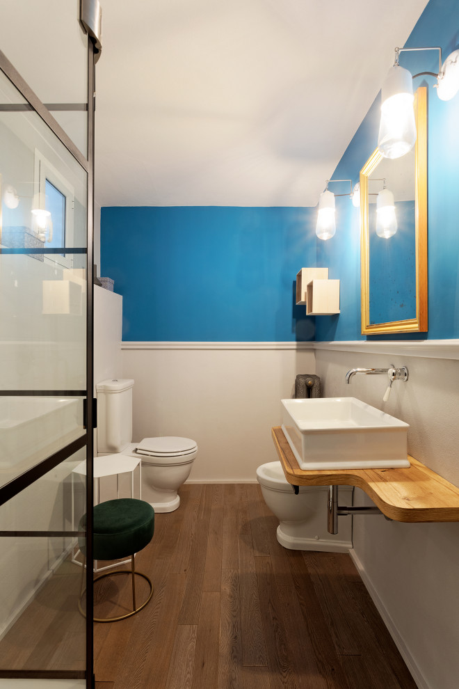 Cette image montre un petit WC et toilettes bohème avec un placard sans porte, WC séparés, un carrelage blanc, un mur bleu, parquet clair, une vasque, un plan de toilette en bois, un plan de toilette blanc, meuble-lavabo suspendu et du papier peint.