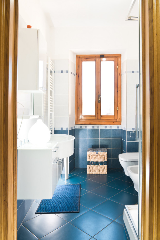 На фото: маленький туалет в стиле модернизм с плоскими фасадами, белыми фасадами, инсталляцией, синей плиткой, керамической плиткой, белыми стенами, полом из керамической плитки, настольной раковиной, стеклянной столешницей, синим полом, белой столешницей и подвесной тумбой для на участке и в саду