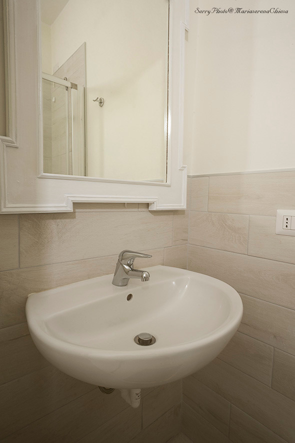 Exempel på ett modernt toalett, med en vägghängd toalettstol, porslinskakel, vita väggar, klinkergolv i porslin och beiget golv