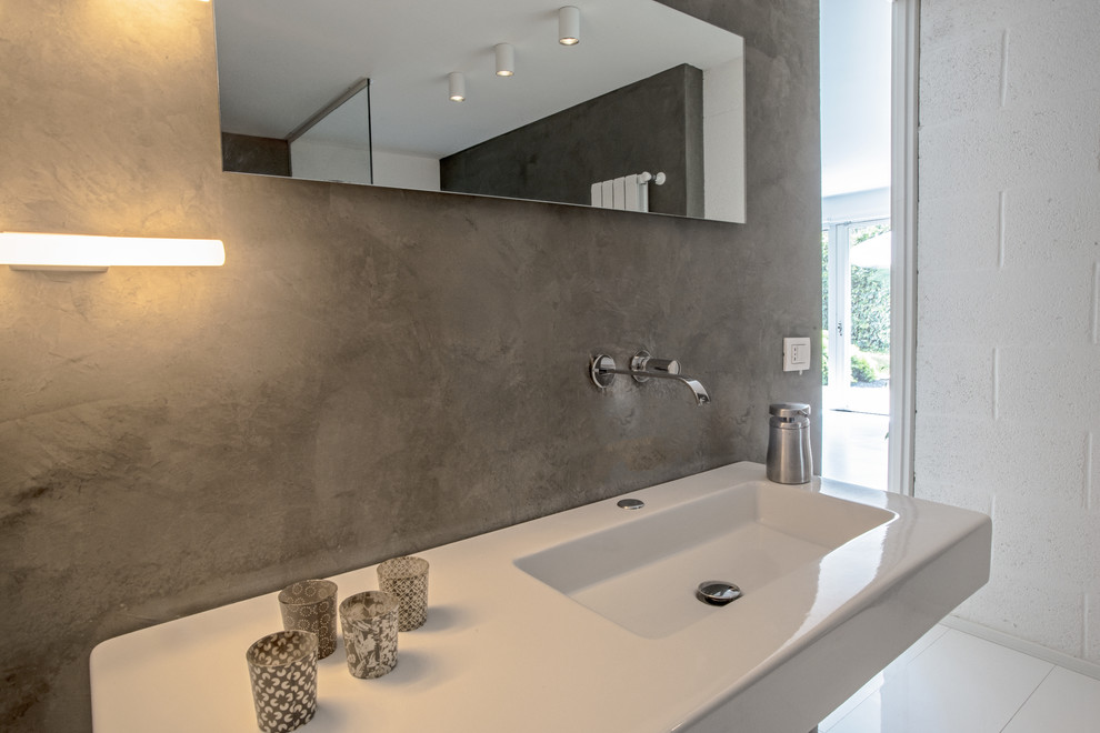 Immagine di un bagno di servizio minimalista con WC sospeso, pareti grigie e lavabo integrato