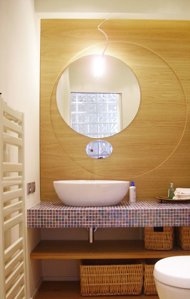 Photo of a small contemporary cloakroom in Venice with a wall mounted toilet, white walls, light hardwood flooring and tiled worktops.