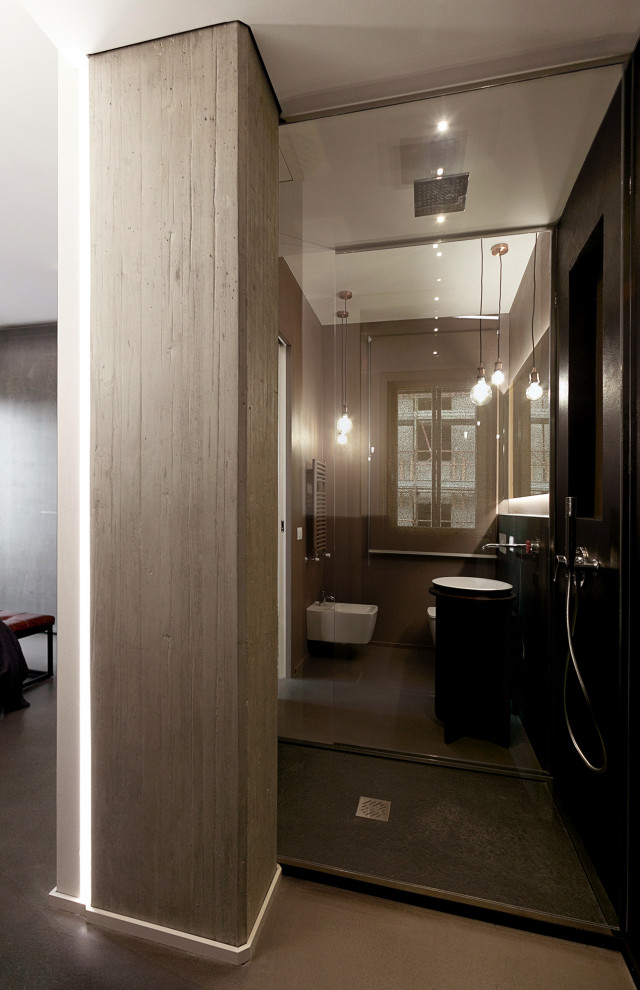 フィレンツェにある高級な小さなインダストリアルスタイルのおしゃれなトイレ・洗面所 (落し込みパネル扉のキャビネット、黒いキャビネット、分離型トイレ、黒いタイル、黒い壁、コンクリートの床、ペデスタルシンク) の写真