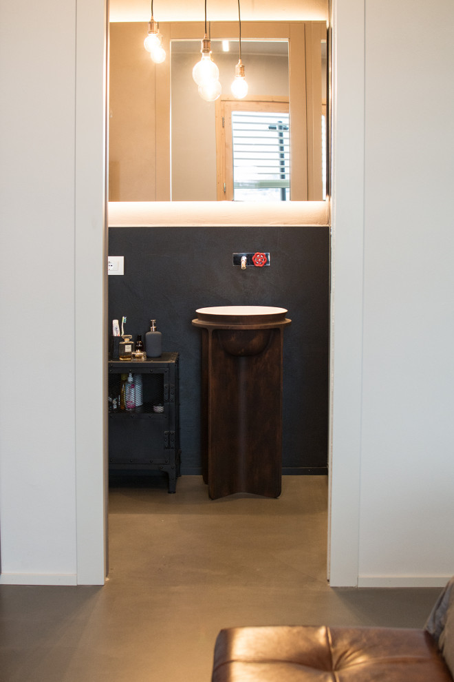 Свежая идея для дизайна: маленький туалет в стиле лофт с фасадами с утопленной филенкой, черными фасадами, раздельным унитазом, черной плиткой, черными стенами, бетонным полом и раковиной с пьедесталом для на участке и в саду - отличное фото интерьера