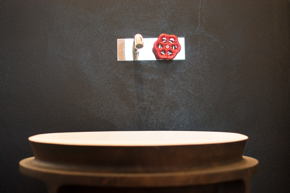 Immagine di un piccolo bagno di servizio industriale con ante con riquadro incassato, ante nere, WC a due pezzi, piastrelle nere, pareti nere, pavimento in cemento e lavabo a colonna