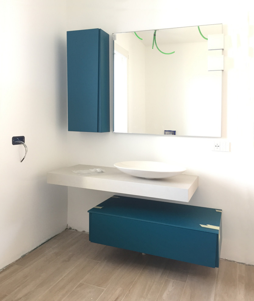 Cette image montre un petit WC et toilettes design avec un placard à porte plane, des portes de placard bleues, un mur blanc, un sol en carrelage de porcelaine, une vasque, un plan de toilette en stratifié, un plan de toilette beige, meuble-lavabo suspendu et un plafond décaissé.