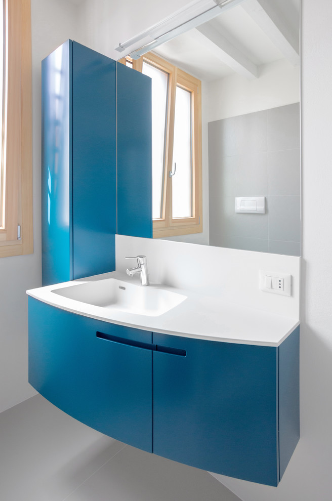 На фото: туалет в современном стиле с плоскими фасадами, синими фасадами и монолитной раковиной с