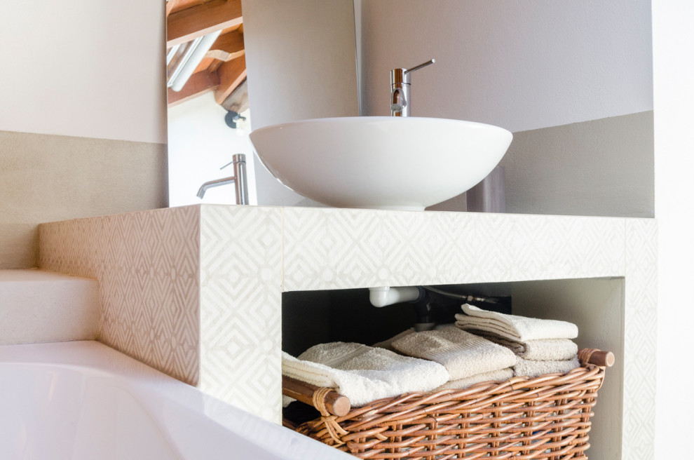 Foto på ett litet funkis beige badrum, med en toalettstol med separat cisternkåpa, beige kakel, porslinskakel, vita väggar, ett fristående handfat, kaklad bänkskiva, beiget golv och en jacuzzi